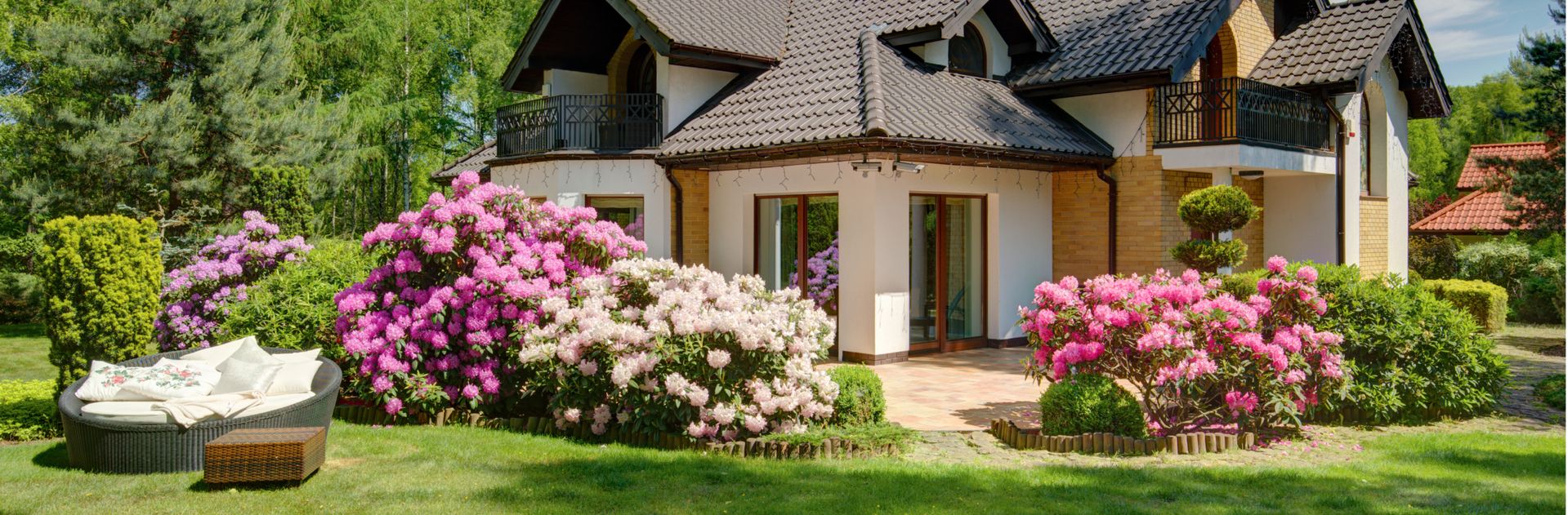 Gepflegter Garten mit blühenden Rhododendren und moderner Terrasse am Einfamilienhaus